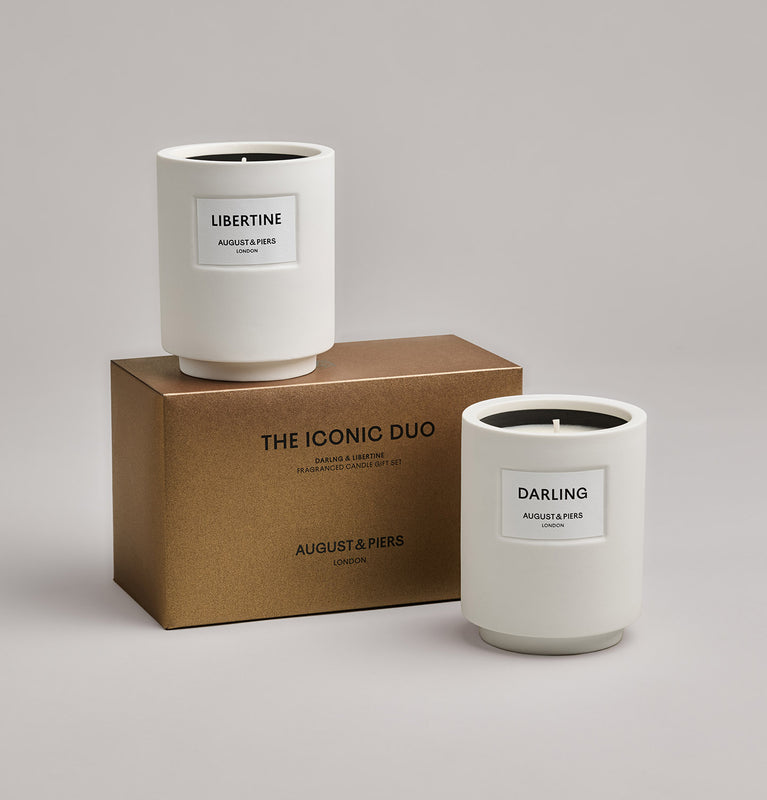 The Iconic Duo Gift Set by AUGUST&PIERS London. Two classic ceramic candles are packaged in a limited-edition dark gold box. This set features the Darling and Libertine candles.