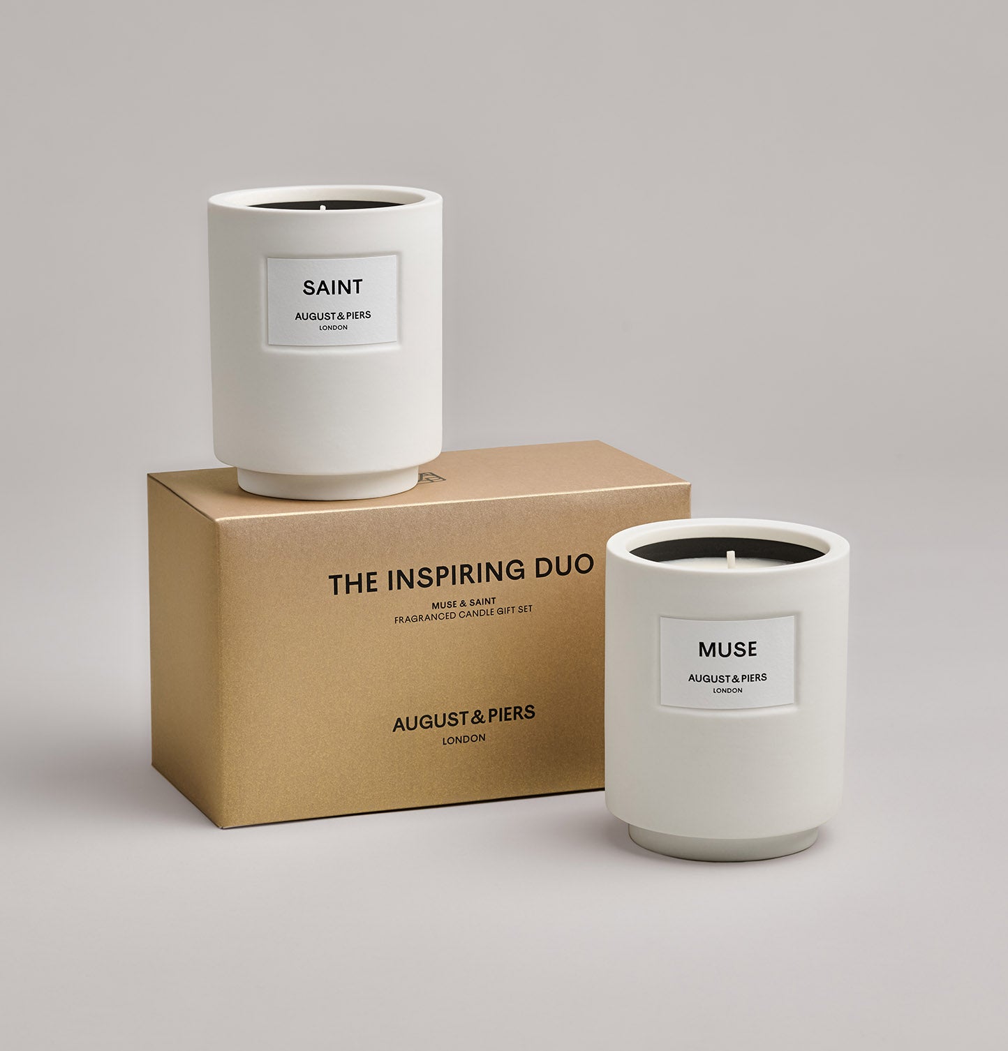 The Inspiring Duo Gift Set by AUGUST&PIERS London. Two classic ceramic candles are packaged in a limited-edition dark gold box. This set features the Muse and Saint candles.