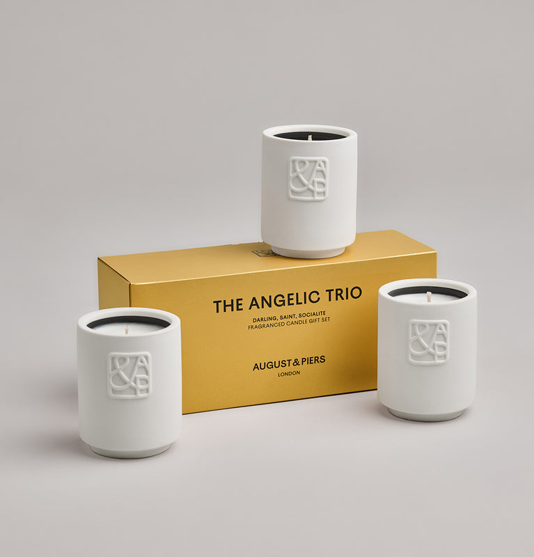 The Angelic Trio Gift Set by AUGUST&PIERS London. Three ceramic mini candles are packaged in a limited-edition gold box. This set features the Darling, Saint, and Socialite candles.